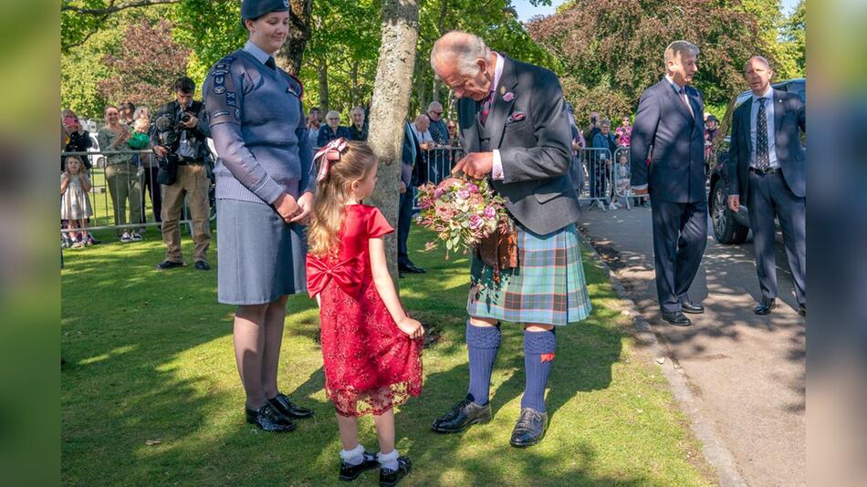 König Charles - im Schottenrock - bekommt zur Begrüßung Blumen überreicht.