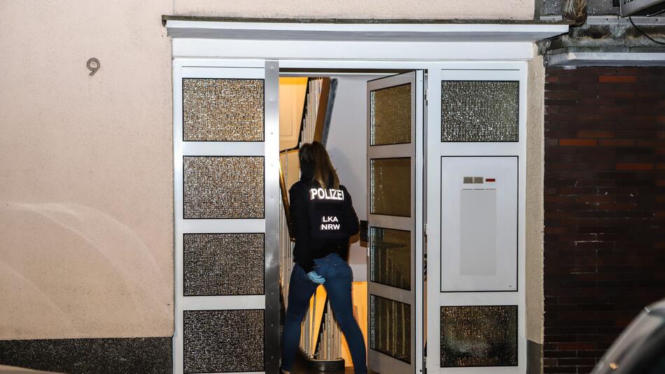 Eine Polizistin geht während einer Razzia in ein Mehrfamilienhaus