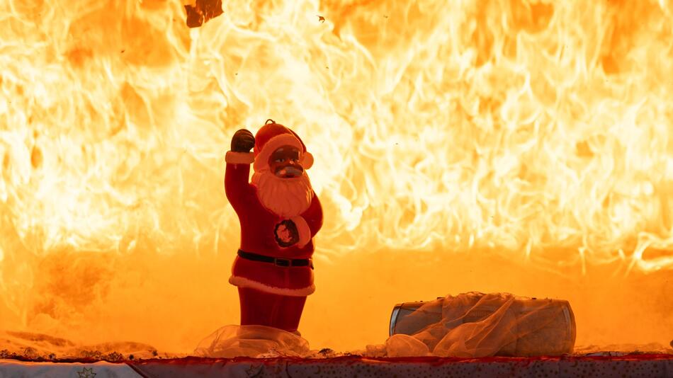 Weihnachtsmannfigur steht vor den Flammen eines Feuers