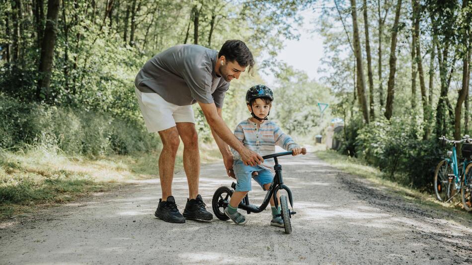 Mann hilft Kind beim Fahrradfahren