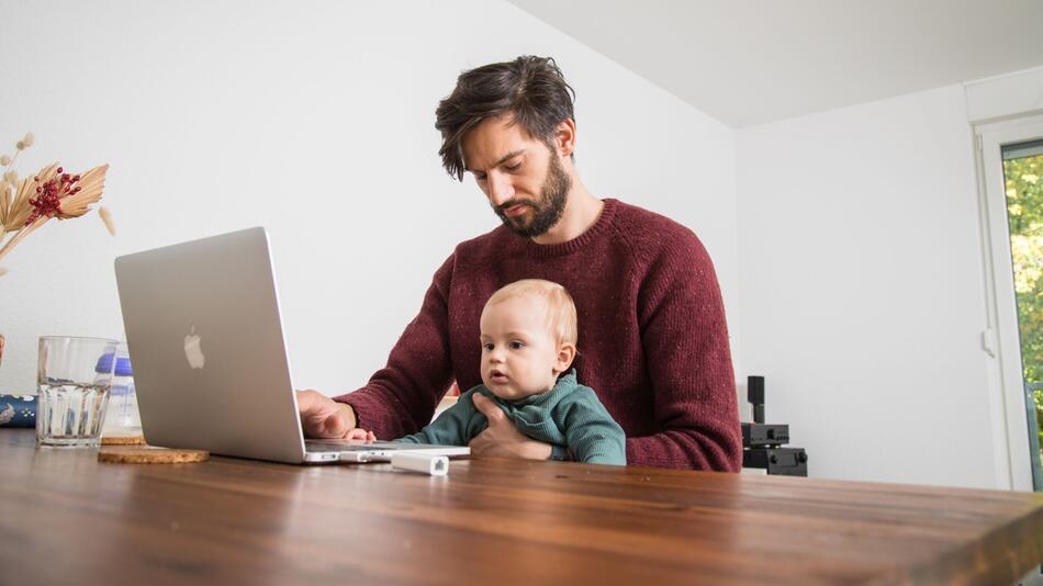 Mann mit Kleinkind im Homeoffice