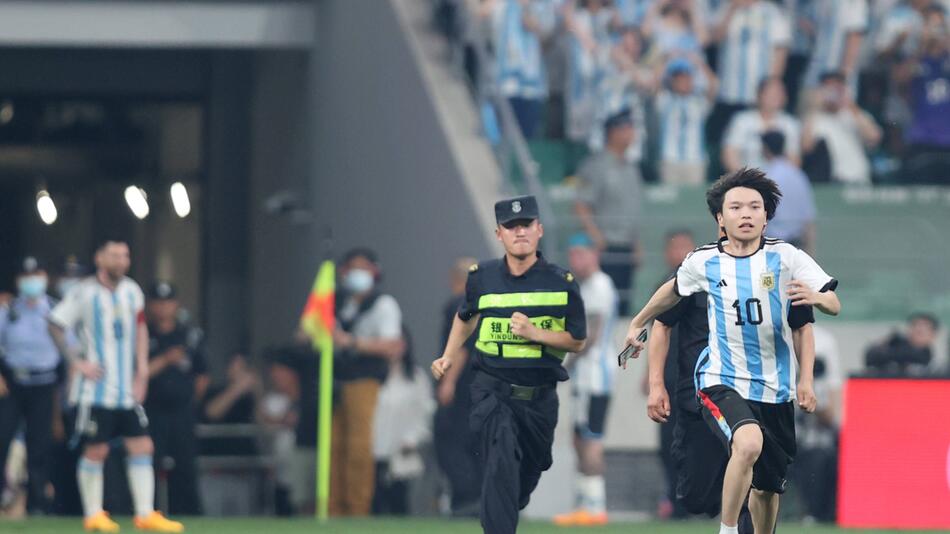 Ein chinesischer Flitzer ist auf der Flucht vor den Ordnern im Stadion in Beijing am 15. Juni 2023
