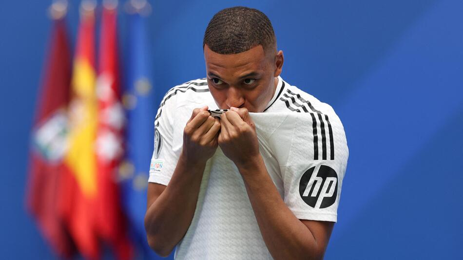 Kylian Mbappe küsst bei seiner Präsentation im Estadio Santiago Bernabeu das Wappen Real Madrids