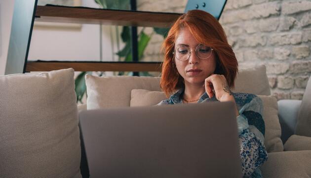 Frau schaut nachdenklich auf einen Laptop