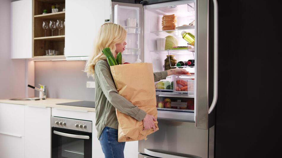 Frau räumt Lebensmittel in den Kühlschrank