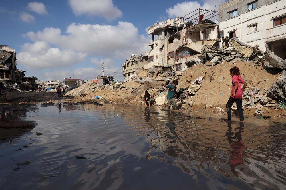 Kinder spielen im Gazastreifen an einer großen Pfütze im Gazastreifen