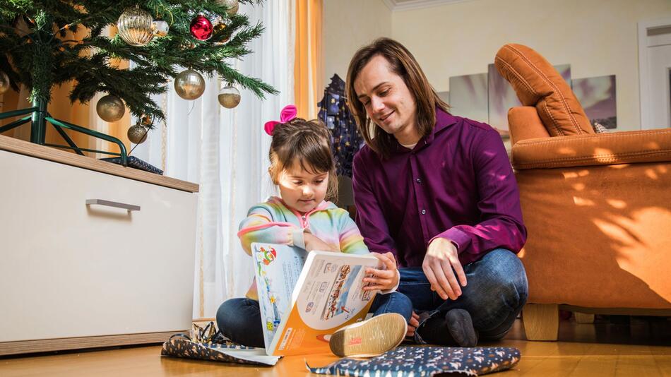 Vater packt mit seiner Tochter Weihnachtsgeschenke aus