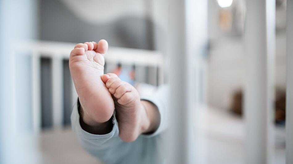 Die Füße eines Babys in einem Kinderbett