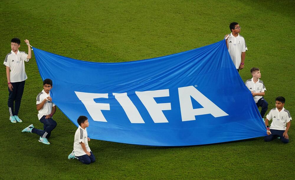 Kinder und Jugendliche präsentieren die Fahne des Fußballweltverbands Fifa