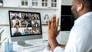 Mann winkt seinen Kollegen in einem Online-Meeting aus dem Homeoffice zu