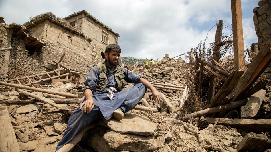 Ein Mann sitzt in den Trümmern eines Hauses nach dem Erdbeben in Afghanistan.