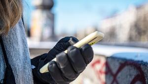 Eine warm angezogene Frau hält bei Kälte ein Handy