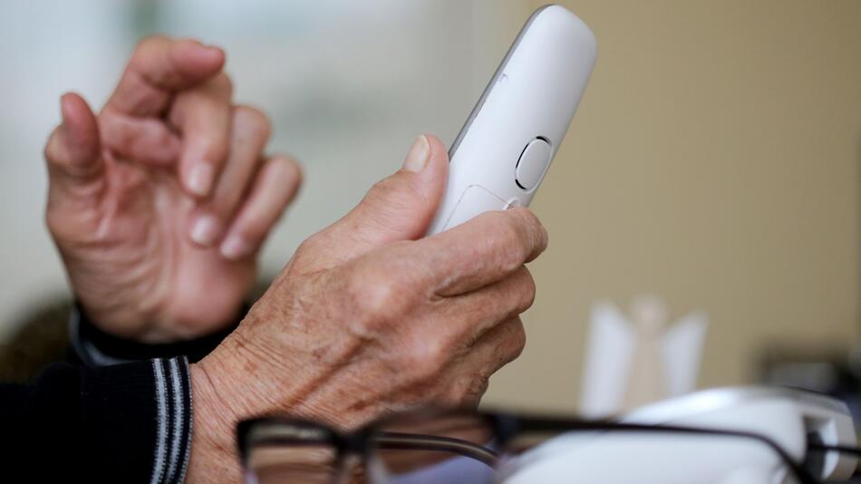 Rentner hält Telefon in der Hand