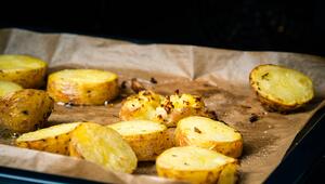 Gebackene Kartoffeln auf einem Blech mit Backpapier im Ofen