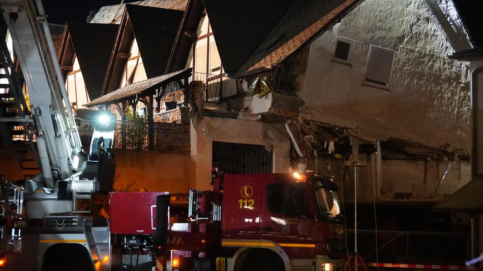 Fahrzeug der Feuerwehr steht vor einem eingestürzten Hotel