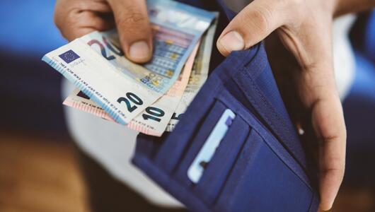 Mann öffnet Geldbörse mit Euro-Scheinen