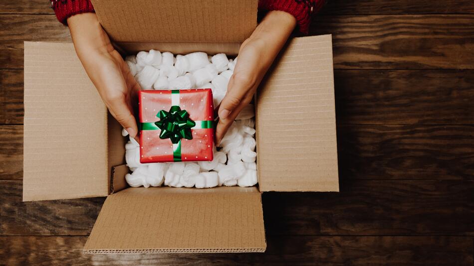 Frau legt ein Weihnachtsgeschenk in einen Karton