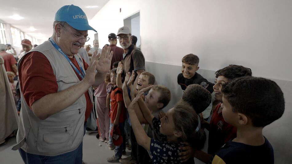 Ein Mann mit UNICEF Cap gibt einer Gruppe Kindern ein High Five.