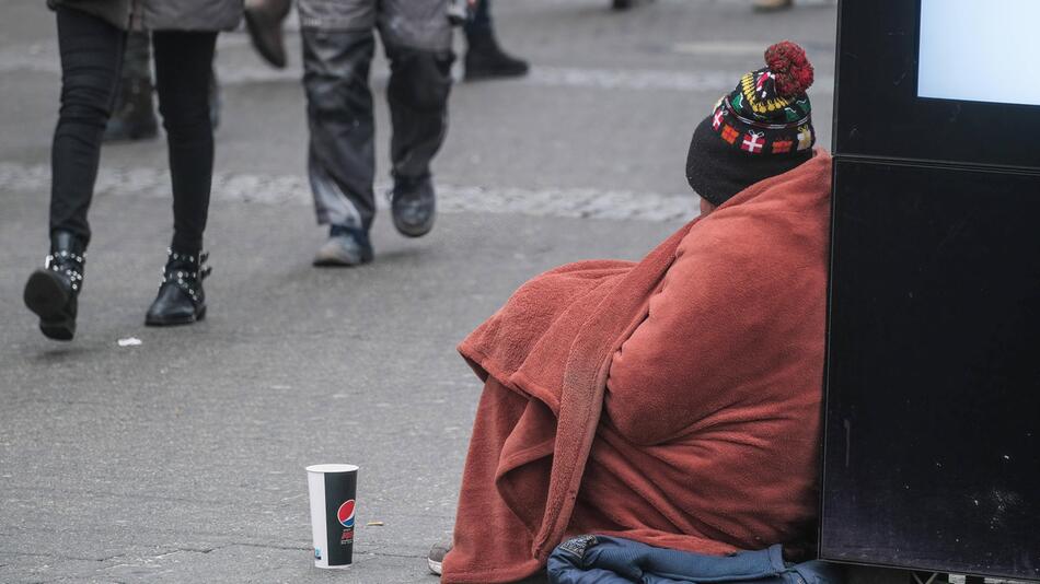 Obdachlose Person sitzt auf der Straße