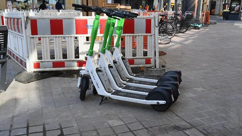 Vier E-Roller stehen am Straßenrand neben einer Bauustelle.