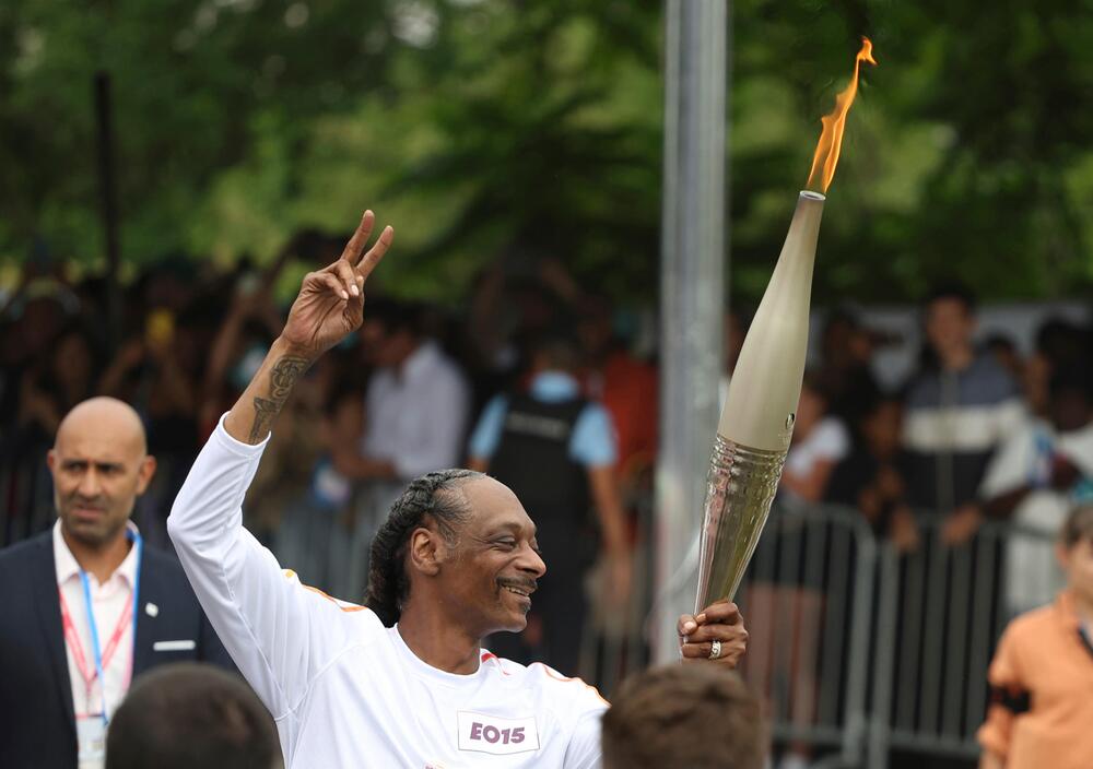 Snoop Dogg trägt das Olympische Feuer durch den Pariser Vorort Saint-Denis.