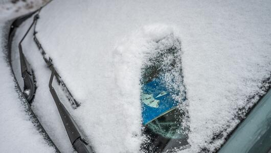 Eine Parkscheibe hinter einer verschneiten Windschutzscheibe