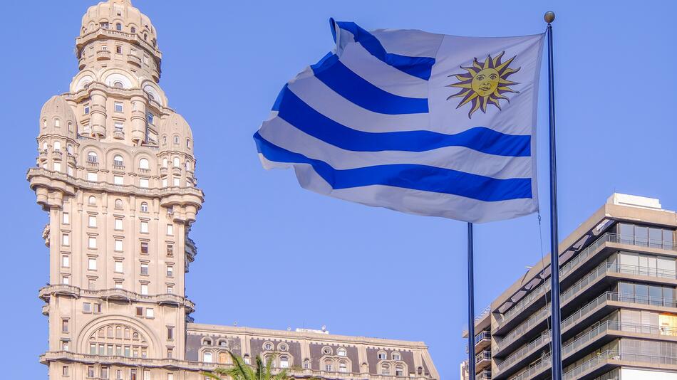 Die Flagge Uruguays mit dem Palacio Salvo-Palast im Hintergrund in Montevideo