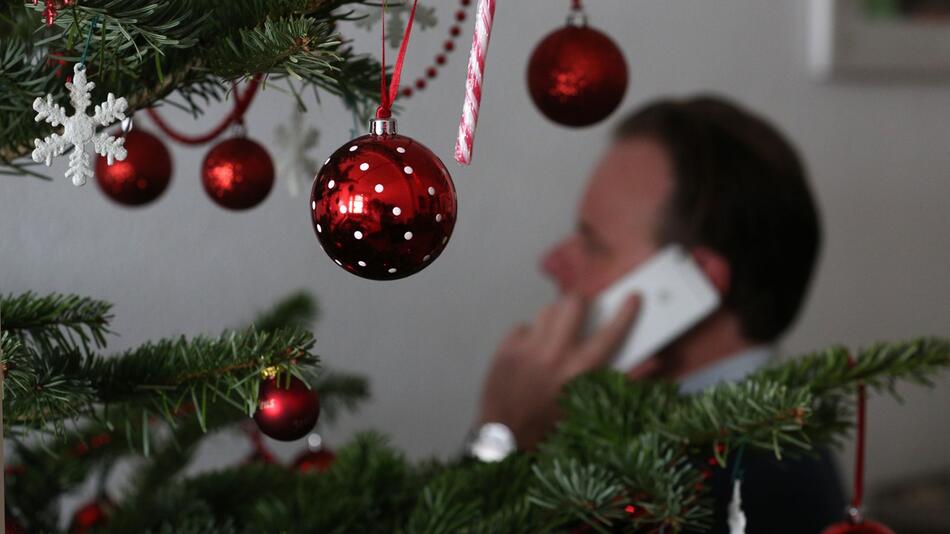 Mann telefoniert neben einem Weihnachtsbaum