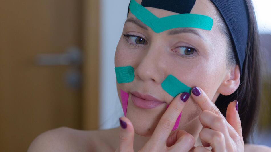 junge Frau taped ihr Gesicht mit Kinesiotape