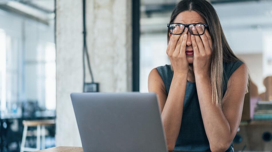 Frau sitzt am PC und schlägt die Hände vors Gesicht