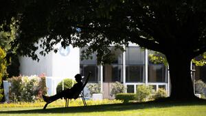 Frau sitzt bei Hitze im Schatten in einem Park