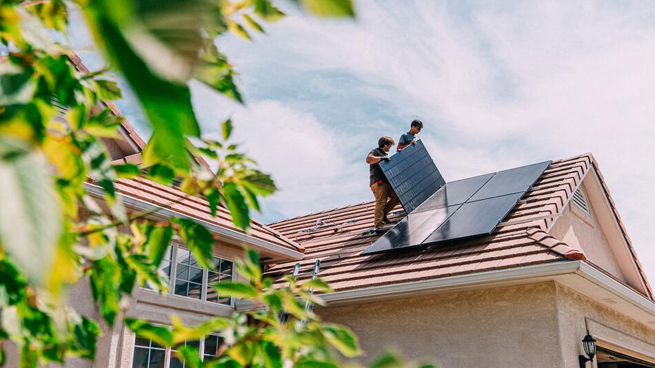 Männer bauen Solaranlage aufs Dach