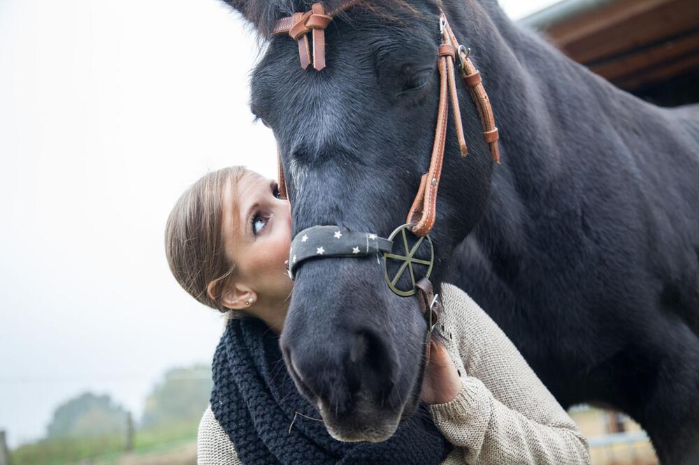 eine Frau schmust mit einem Pony