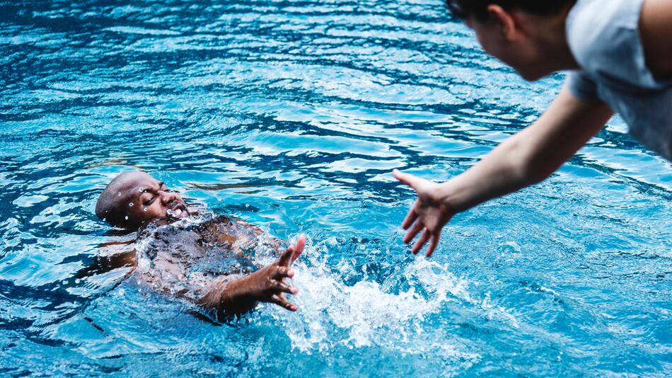 Person zieht Ertrinkenden aus dem Wasser