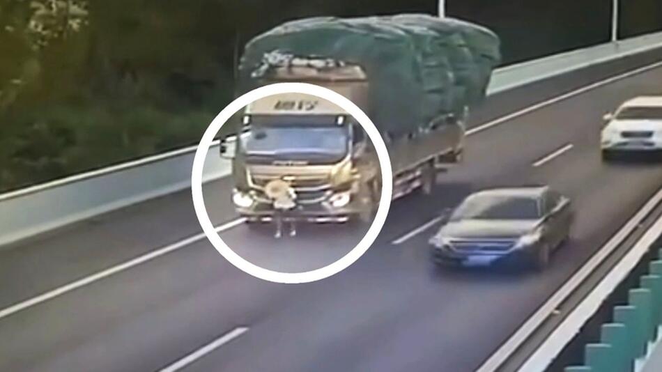 Ein LKW-Beifahrer auf einer Autobahn in China vor einem LKW