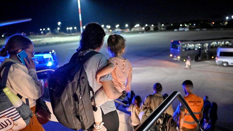 Eine Frau mit Kind auf dem Arm verlässt ein Flugzeug