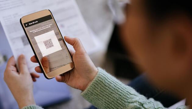 Ältere Frau scannt QR-Code auf einem Brief
