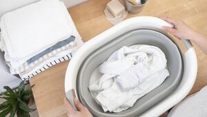 In einem Wäschekorb, der auf einer Arbeitsplatte aus Holz steht, liegt weiße Wäsche.