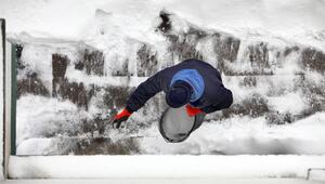 Mann streut Salz auf einen vom Schnee geräumten Gehweg.