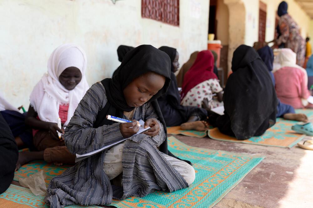 Ein Mädchen sitzt auf dem Boden und malt.