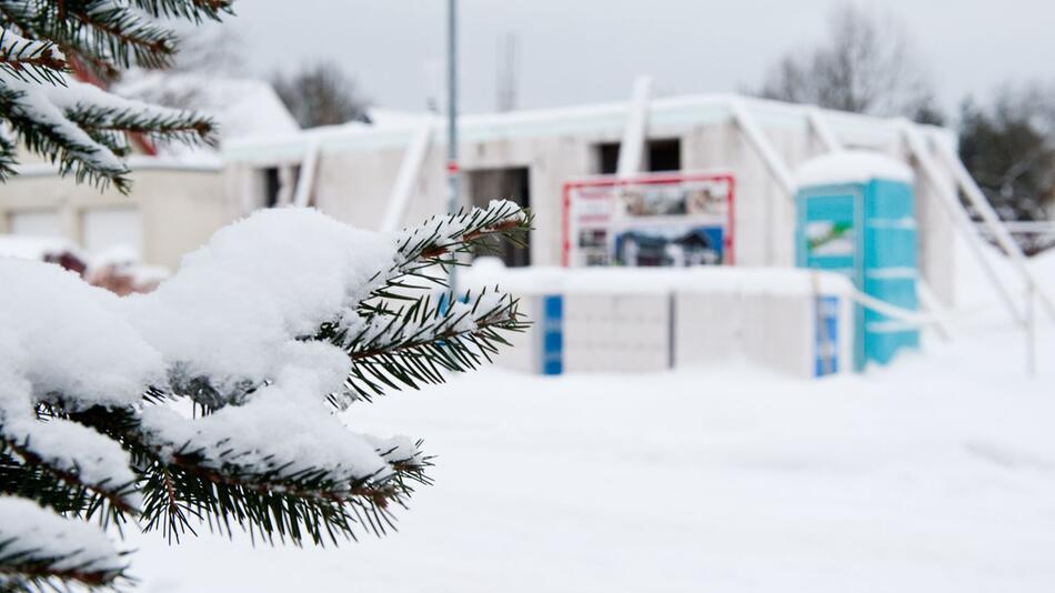 Schnee bedeckte Baustelle eines Einfamilienhauses