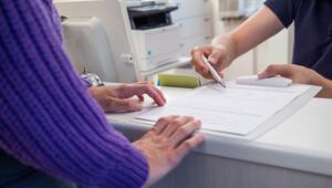 Arzthelfer übergibt Patientin einen Anamnesebogen