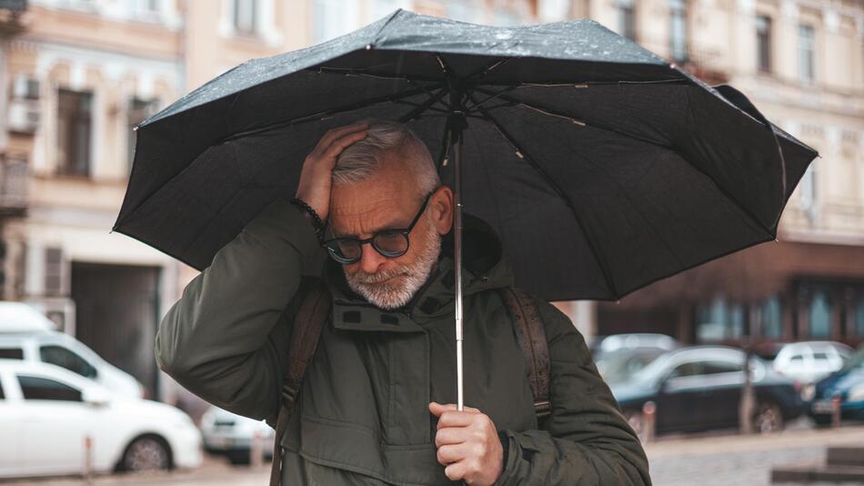 Mann fasst sich bei Regen an den Kopf