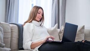 Eine Frau nutzt einen Laptop auf dem Sofa