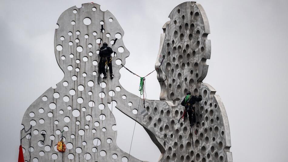 Aktivisten klettern auf Skulptur Molecule Man in der Spree