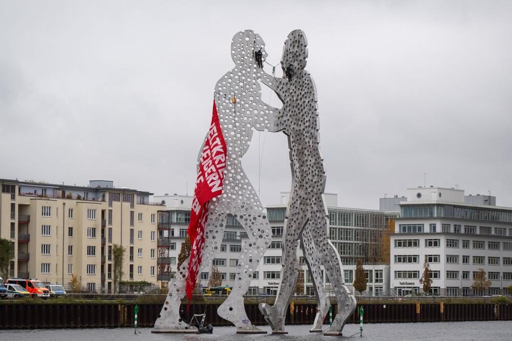 Aktivisten klettern auf Skulptur Molecule Man in der Spree