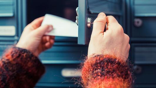 Person holt Brief aus einem Briefkasten