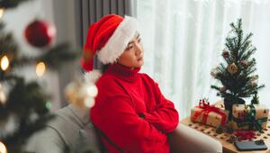 Frau sitzt genervt neben einem Weihnachtsbaum