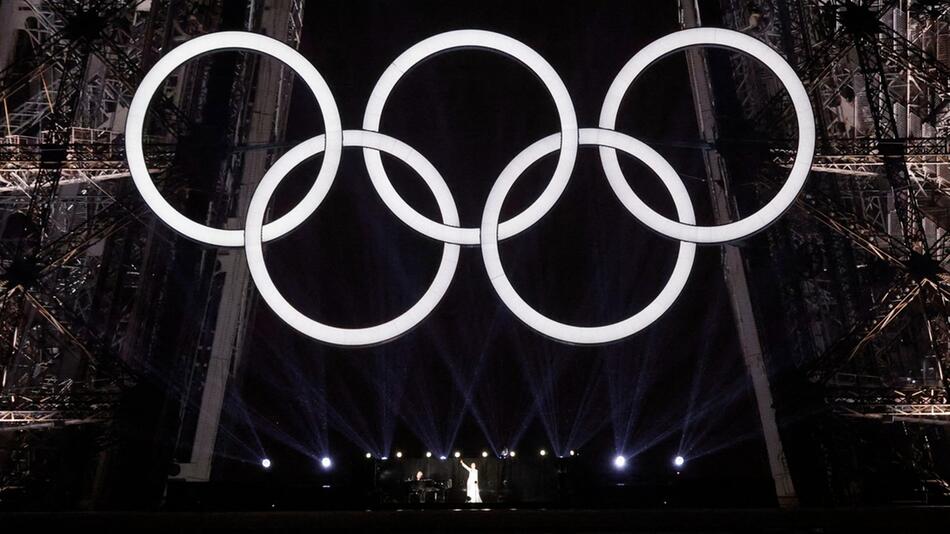 Céline Dion auf dem Eiffelturm unter den olympischen Ringen.