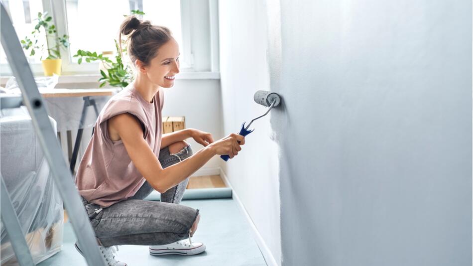 Frau streicht im sitzen eine Wand.